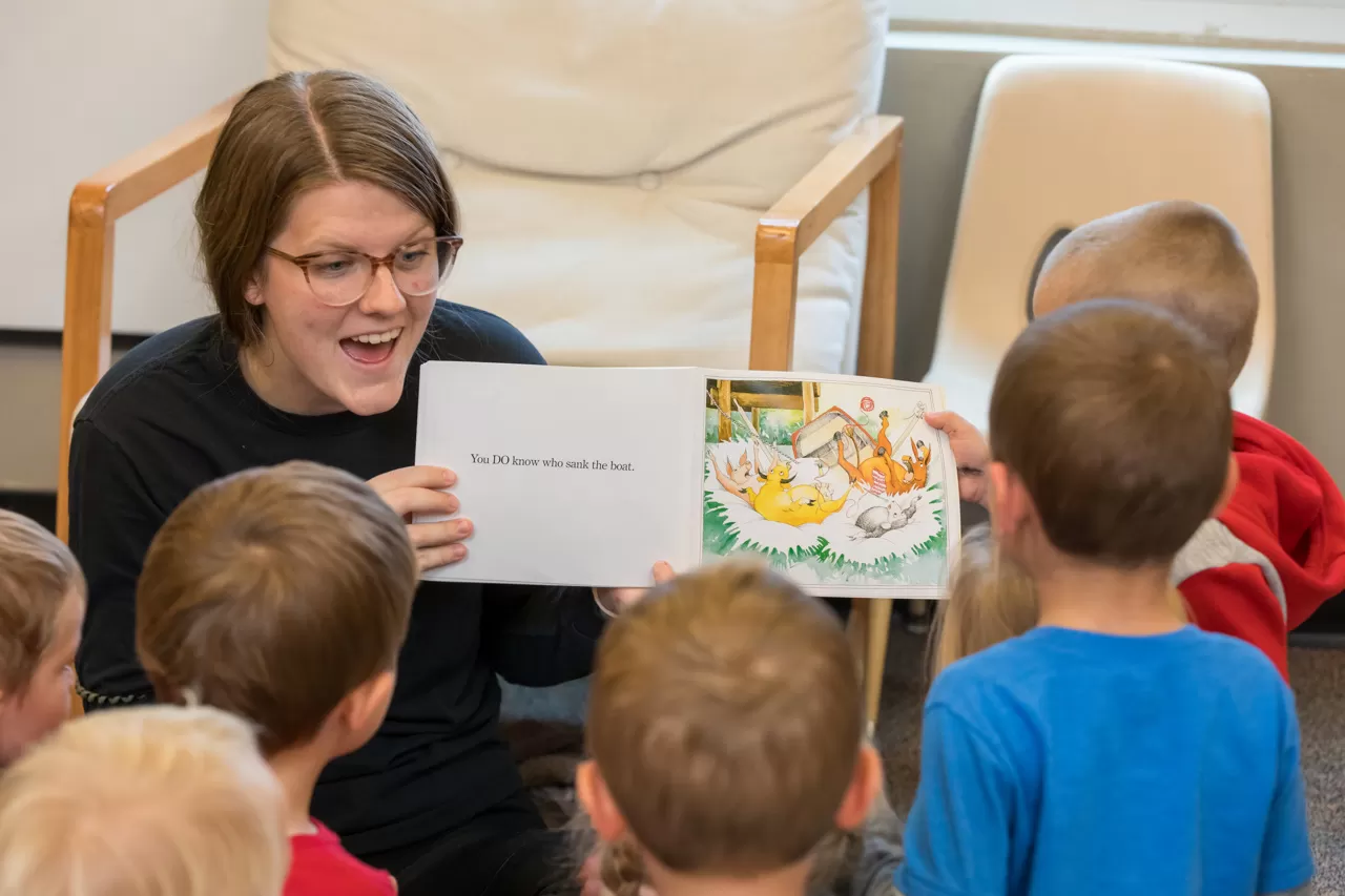 YMCA Child Care leader reading a story to a group of kids