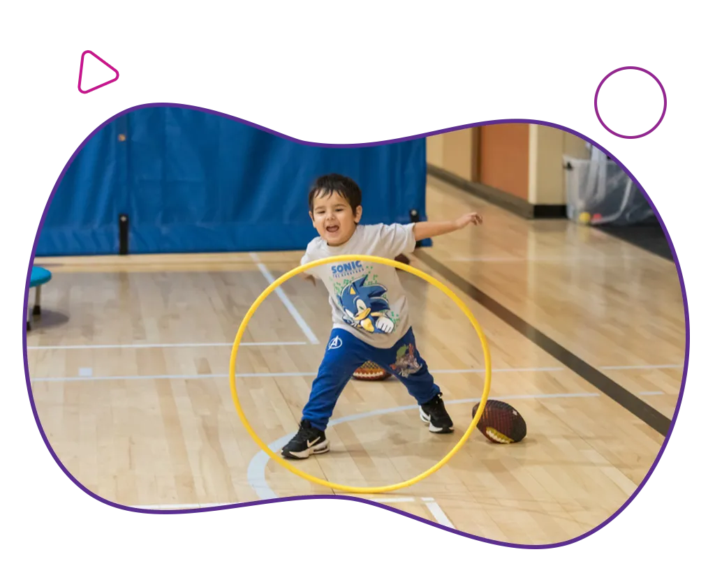 toddler playing with a hula hoop in the YMA gym