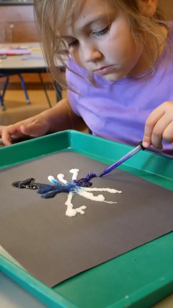 Child using a liquid dropper to color an art project
