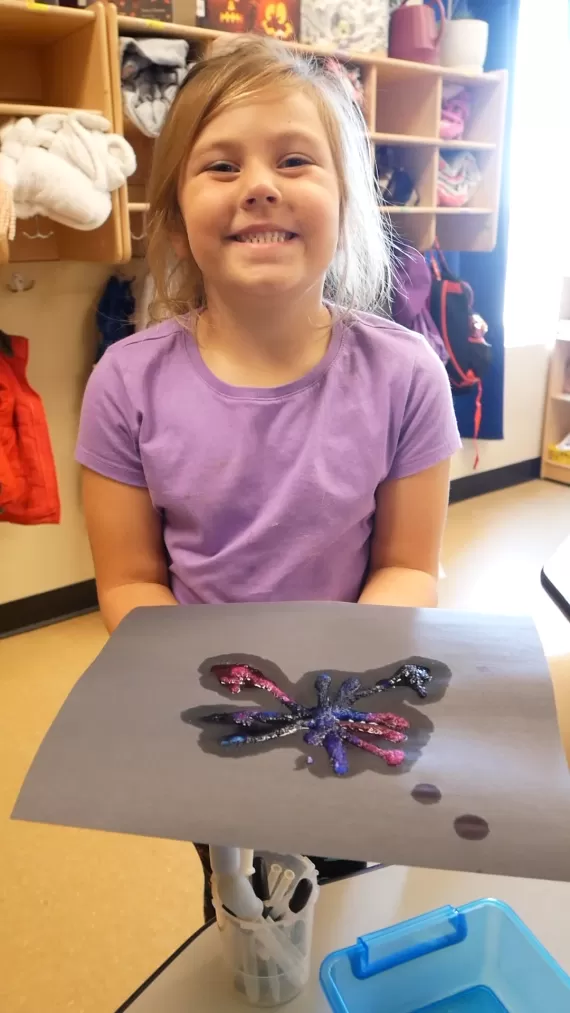Smiling child holding up their art project