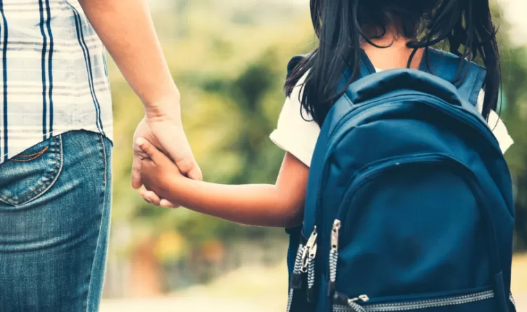 mother and child holding hands walking to school