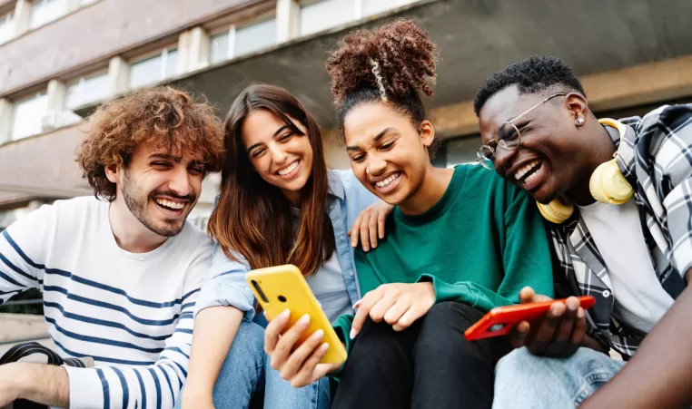 4 friends looking at a mobile phone and laughing