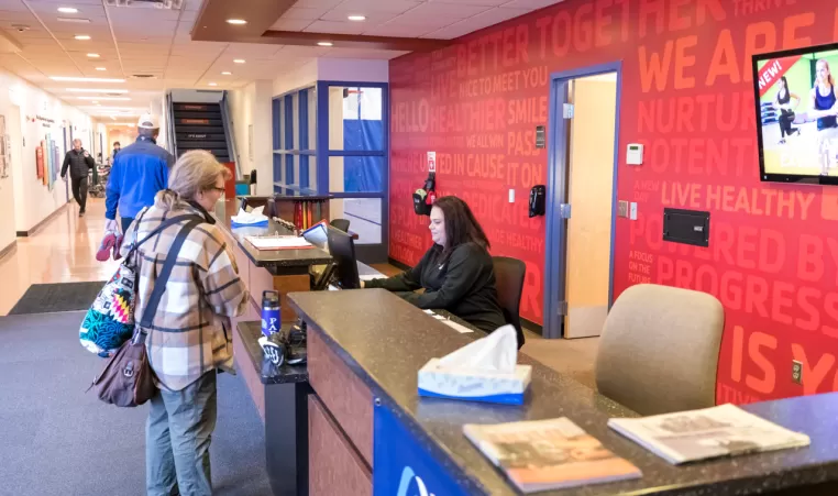 woman checking in at a gym's front desk