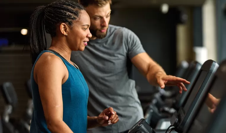 woman in the gym on a treadmill with a personal trainer