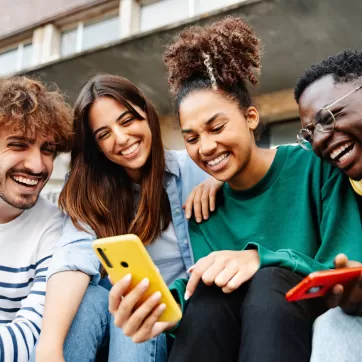 4 friends looking at a mobile phone and laughing