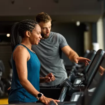 woman in the gym on a treadmill with a personal trainer