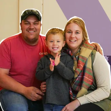 2 parents and a child smiling at the camera