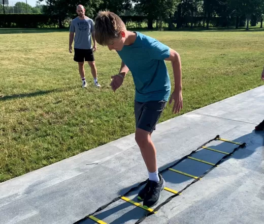 young boy running through agility ladder