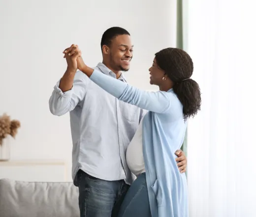 romantic pregnant couple dancing at home